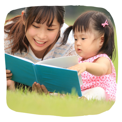 Mother reading to small child in grass